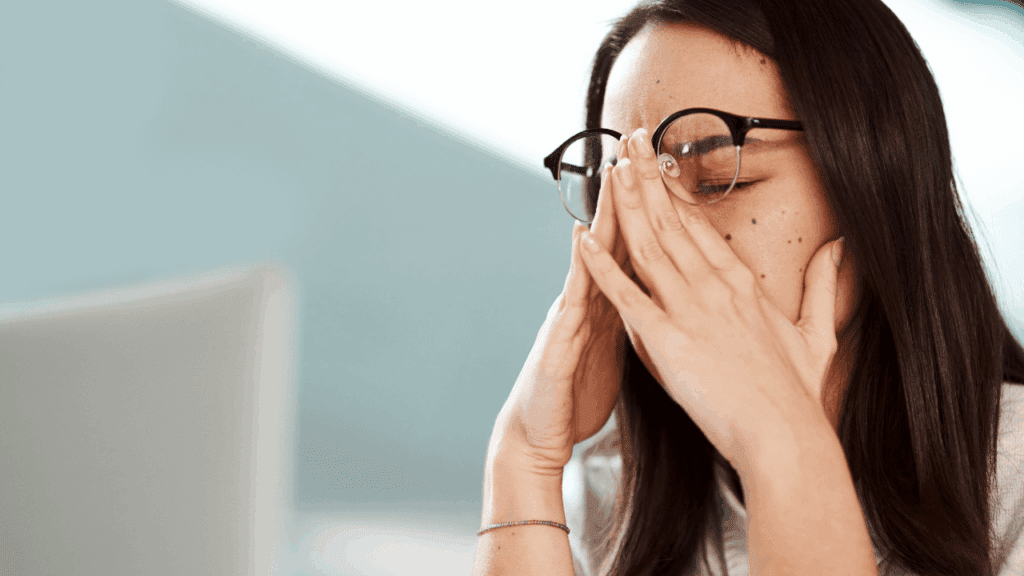 A woman wearing glasses that cover her eyes, symbolizing the challenges of navigating midlife crisis stages.