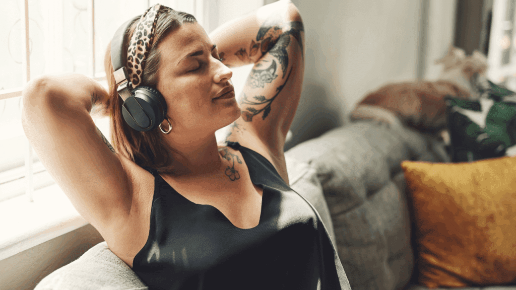 A woman wearing headphones, relaxing on a couch, enjoying a moment of peace and calm with PSYCH-K® in mind.
