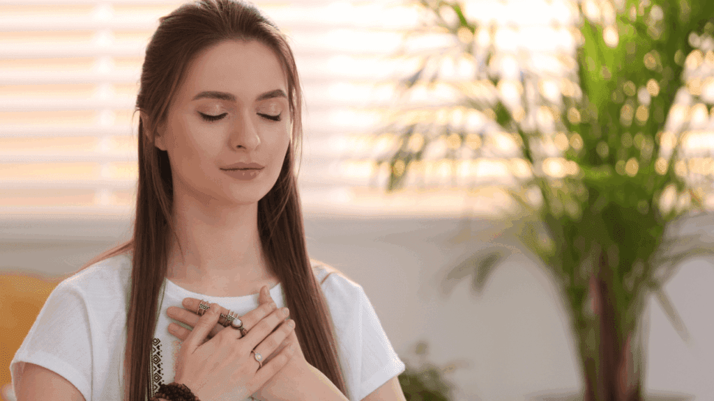 A woman sitting on a couch, hands clasped together, reflecting on her thoughts during a midlife crisis.