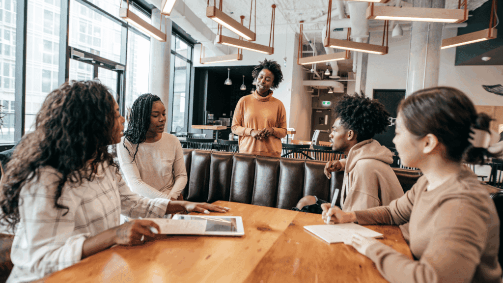 A group of women discussing emotional intelligence in leadership around a table in a modern office setting.