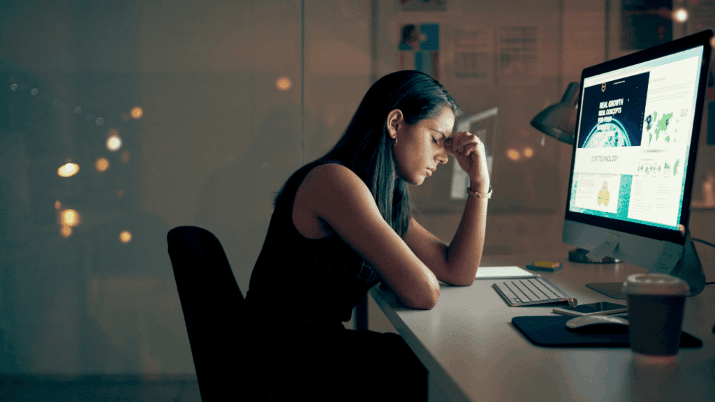 A woman at a desk, visibly stressed, with her head in her hands, reflecting traditional burnout advice.