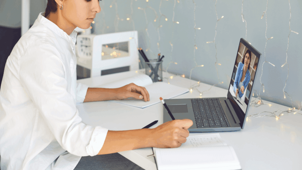 A woman sitting at a desk with a laptop and pen, exploring business coaching and executive coaching concepts.