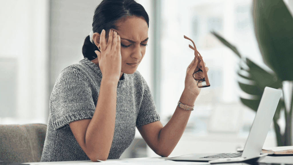 A woman sits at her desk with her head in her hands, reflecting on starting over in life.